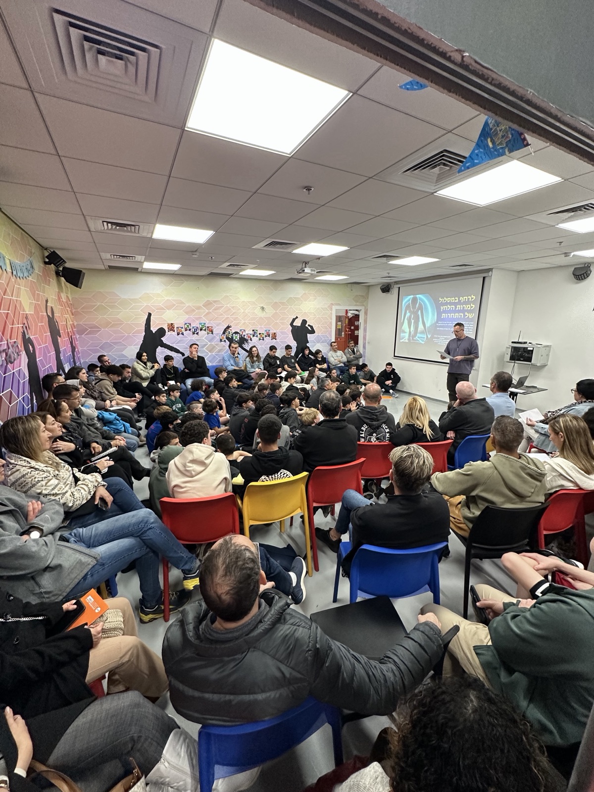 עמית קליגר מרצה לחדר מלא בהרצאה לקבוצת ספורט