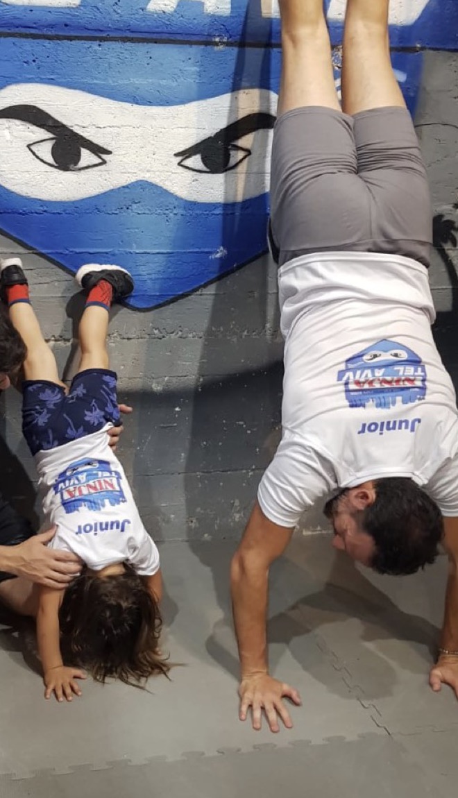 עמית והבן שלו עומדים על הידיים על קיר הנינג'ה